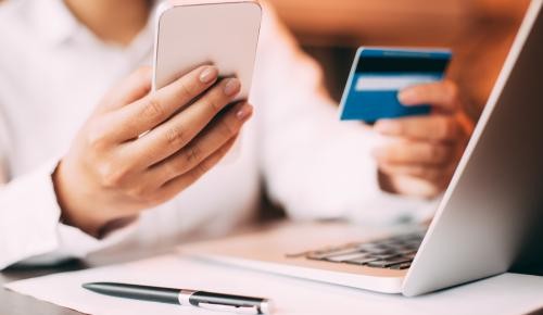 Person mit Kreditkarte, Handy und Laptop Person mit Kreditkarte, Handy und Laptop